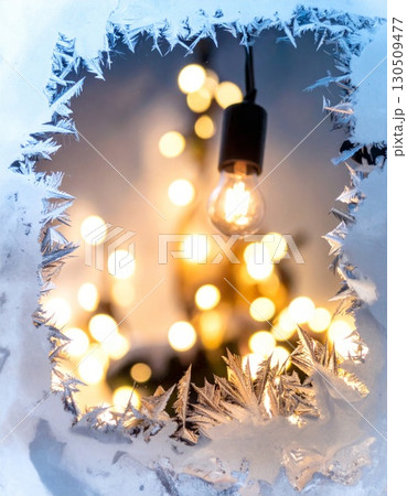 Illuminated Bulb with Winter Frost on Window and Bokeh Lights Background 130509477