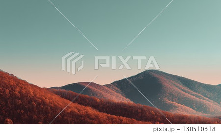 Vibrant autumn trees cover the layered mountains illuminated beneath a soft gradient sky 130510318