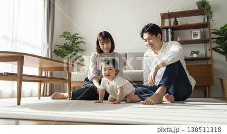 ハイハイする赤ちゃんを見守る夫婦　家族イメージ 130511318