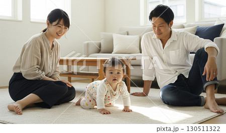 ハイハイする赤ちゃんを見守る夫婦　家族イメージ 130511322