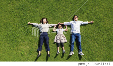 芝生の上で寝転がる夫婦と娘　家族イメージ 130511331