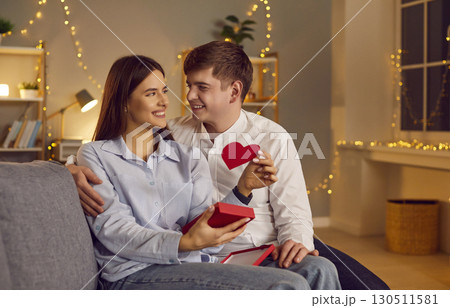 Couple in the evening sitting on the sofa hugging in the bedroom with garlands 130511581