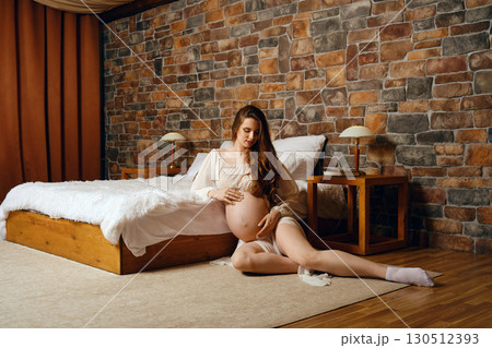 Expecting mother relaxing in a cozy bedroom with a rustic ambiance 130512393
