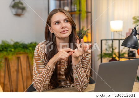 Young woman counts finished tasks on fingers folds digits reviews done list with calm focus indoors Young woman counts finished tasks on fingers folds digits reviews done list with calm focus indoors 130512631