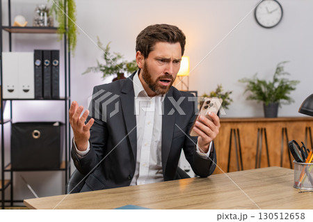 Middle-aged businessman frustrated reading client rejection on smartphone frowns at news loses game 130512658