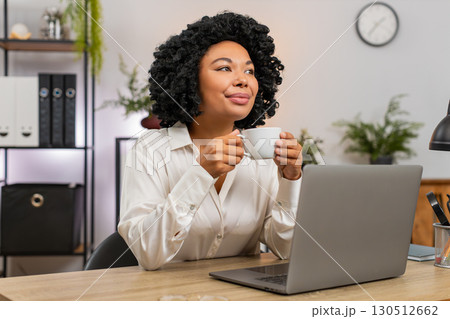 African American businesswoman drinks coffee thinking near window resting from work for inspiration 130512662