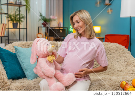 Pregnant woman hugging pink bunny toy showing love waiting baby arrival sweet tender moment of hope 130512664