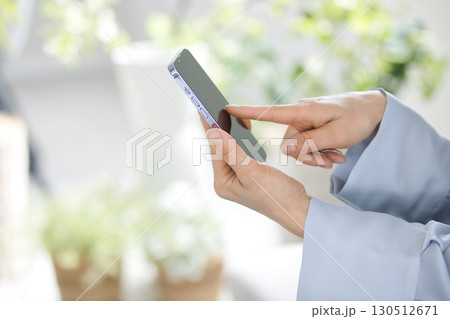 スマホを操作するミドル女性の手元 130512671