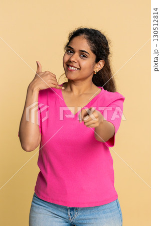 Indian woman making call me hand gesture, smiling playfully towards camera, signaling phone call Indian woman making call me hand gesture, smiling playfully towards camera, signaling phone call 130512814