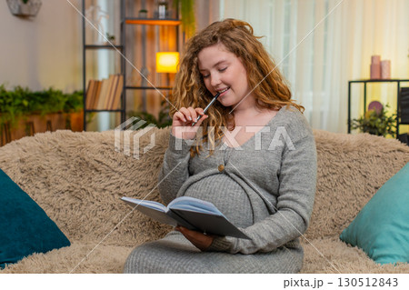 Pregnant young woman writing in diary to do list at home, thoughtful and focused, future planning Pregnant young woman writing in diary to do list at home, thoughtful and focused, future planning 130512843