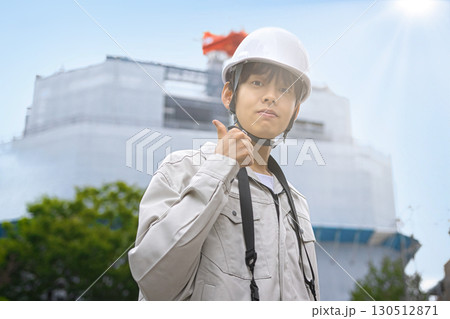 工事現場でタブレットを見る作業服の若いビジネスマン 130512871