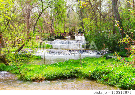 Tourists walking on bridge over waterfall in lush green park, monasterio de piedra, spain 130512973