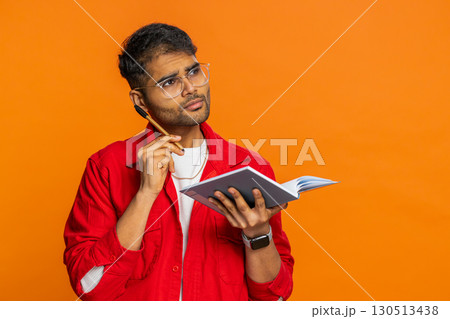 Thoughtful Indian man making notes, writing down thoughts with pen into notepad notebook, good idea Thoughtful Indian man making notes, writing down thoughts with pen into notepad notebook, good idea 130513438