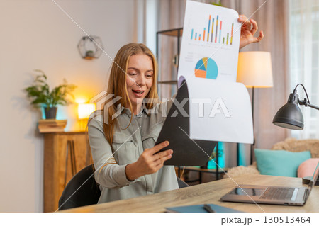 Happy mature businesswoman freelancer analyzing graph documents sitting at home office table desk Happy mature businesswoman freelancer analyzing graph documents sitting at home office table desk 130513464