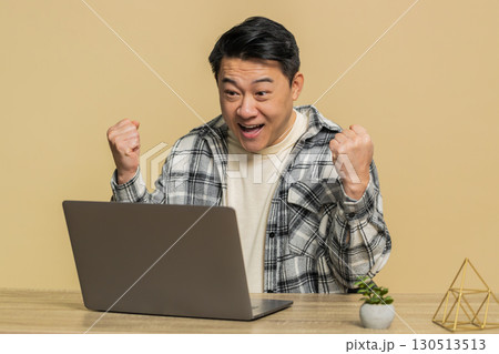 Happy man working on laptop shocked by victory celebrate winning goal achievement, good career news 130513513