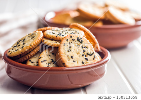 Crispy round salted crackers in bowl on white table. Crispy round salted crackers in bowl on white table. 130513659