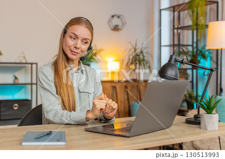 Mature female customer service representative with headset using laptop computer at home office desk 130513993