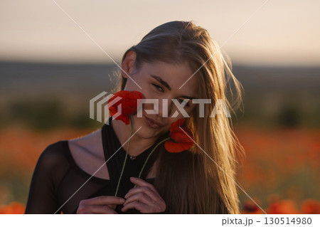 Woman Poppies Field: Girl holds flowers, poses during golden hour in poppy field for photography. 130514980