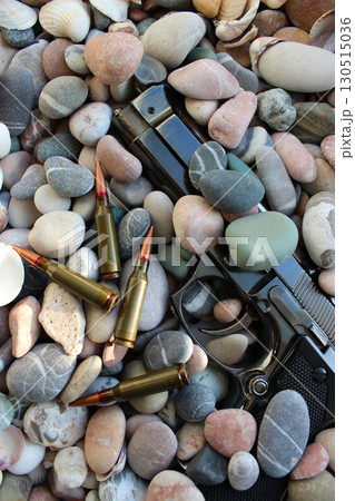 Bullets Near Discarded Handgun In A Small Pebbles On Sea Shore Bullets Near Discarded Handgun In A Small Pebbles On Sea Shore 130515036