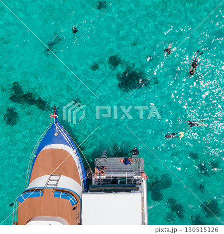 Aerial view of scuba divers swimming on water surface and climbing up on platform at Racha Island Aerial view of scuba divers swimming on water surface and climbing up on platform at Racha Island 130515126
