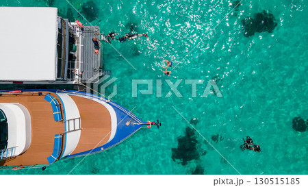 Aerial view of scuba divers swimming on water surface and climbing up on boat platform Aerial view of scuba divers swimming on water surface and climbing up on boat platform 130515185
