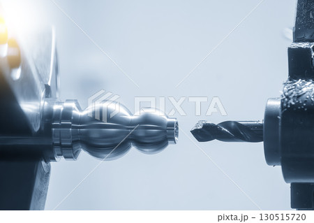 Close up scene the CNC lathe machine hole drilling process the metal shaft parts in the blue tone scene. 130515720