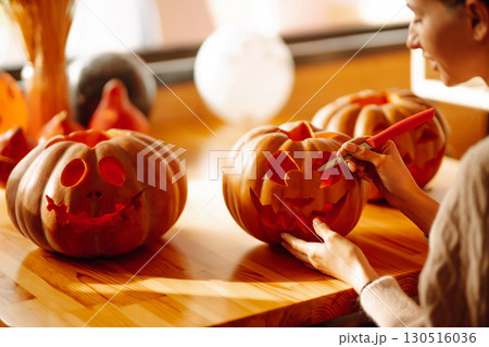 Young woman cutting with knife character face on pumpkin object preparation to halloween holiday. 130516036