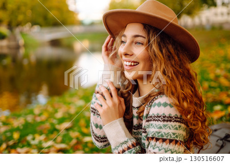 Portrait of a stylish smiling woman walking in park. street style in hat. Concept of nature, relax. 130516607