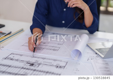 Asian adult architect hands expertly drafting detailed architectural blueprints at office desk designing innovative building solutions engineering plans 130516645