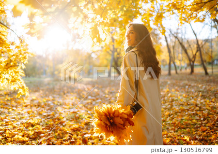 Young woman taking pictures in the autumn forest. Lady Walking In Fall Park With Yellow Foliage. 130516799