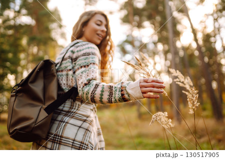 Hand of a stylish tourist with a backpack holds to the soft golden pampas grass in the autumn season Hand of a stylish tourist with a backpack holds to the soft golden pampas grass in the autumn season 130517905