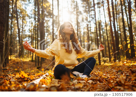 Beautiful woman practices yoga in the autumn forest. Lifestyle and meditation concept. Beautiful woman practices yoga in the autumn forest. Lifestyle and meditation concept. 130517906