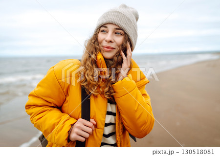 A beautiful young tourist woman in a yellow jacket with a backpack enjoys life near the sea. Travel. A beautiful young tourist woman in a yellow jacket with a backpack enjoys life near the sea. Travel. 130518081