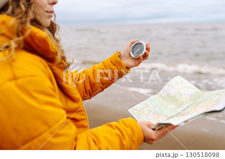 Traveler explorer young woman holding compass, map in hands on beach near the sea. Active lifestyle. Traveler explorer young woman holding compass, map in hands on beach near the sea. Active lifestyle. 130518098
