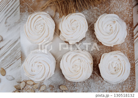 Pumpkin marshmallow meringues on a rustic wooden table, top view with powdered sugar 130518132