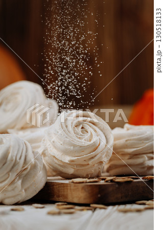 Pumpkin marshmallow sweets with powdered sugar falling, rustic autumn wooden background Pumpkin marshmallow sweets with powdered sugar falling, rustic autumn wooden background 130518133