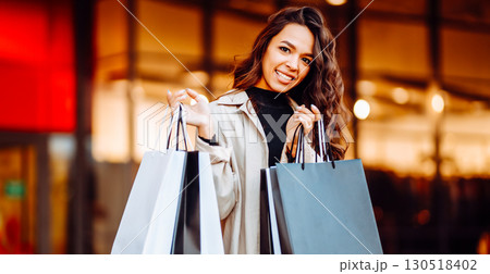 Young woman with shopping bags near mall. Spring Style. Consumerism, purchases, shopping, lifestyle Young woman with shopping bags near mall. Spring Style. Consumerism, purchases, shopping, lifestyle 130518402