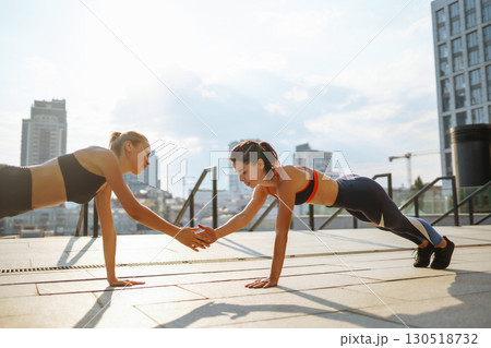 Two Young woman in sports outfit doing exercises outdoors in the morning. Sport, sports training. Two Young woman in sports outfit doing exercises outdoors in the morning. Sport, sports training. 130518732