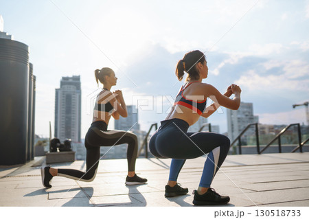 Two Young woman in sports outfit doing exercises outdoors in the morning. Sport, sports training. Two Young woman in sports outfit doing exercises outdoors in the morning. Sport, sports training. 130518733