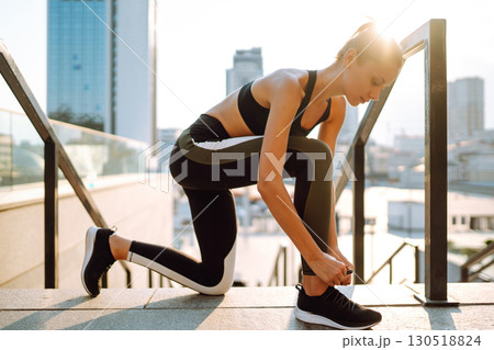 Young woman getting ready for jogging outdoors while lacing her sneakers. Health and sport concept. Young woman getting ready for jogging outdoors while lacing her sneakers. Health and sport concept. 130518824