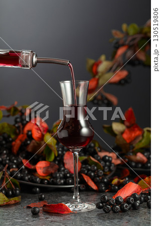 Black chokeberry liqueur and fresh berries on a black table. Black chokeberry liqueur and fresh berries on a black table. 130519806