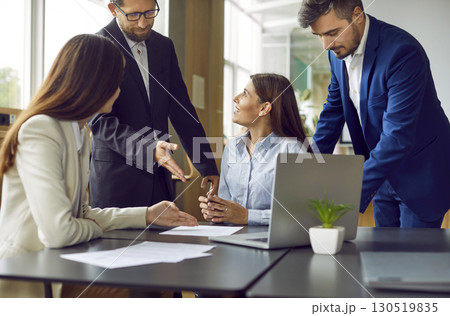 Team of business people meeting by office table, working with documents, talking and using laptop Team of business people meeting by office table, working with documents, talking and using laptop 130519835