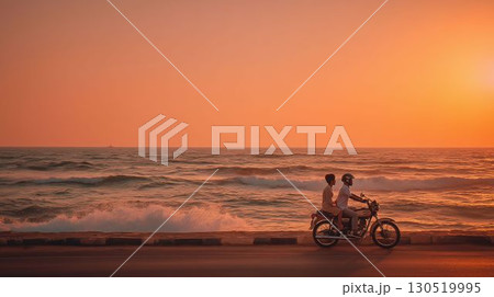 夕暮れ時の海岸を走るカップルライダー 130519995