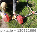 man hands holding funnel and plastic bottle with pink liquid to fill petrol hand mower, refueling trimmer before mowing lawn 130521696