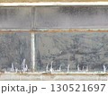 an old, peeling, dilapidated wall made of a dull-textured hard material, stitched with metal ties with a corrosion effect, a fragment of the outer wall of a utility building with paint smudges 130521697