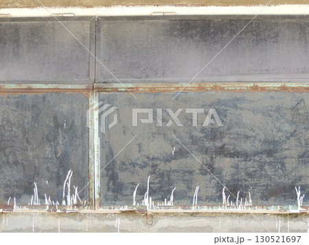 an old, peeling, dilapidated wall made of a dull-textured hard material, stitched with metal ties with a corrosion effect, a fragment of the outer wall of a utility building with paint smudges 130521697