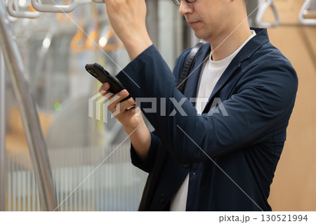 電車内でスマートフォンを持つ男性 130521994