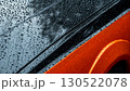 Rain droplets on a sleek orange car detail creating an abstract blurred effect 130522078