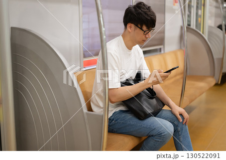 電車内でスマホを見る男性 130522091