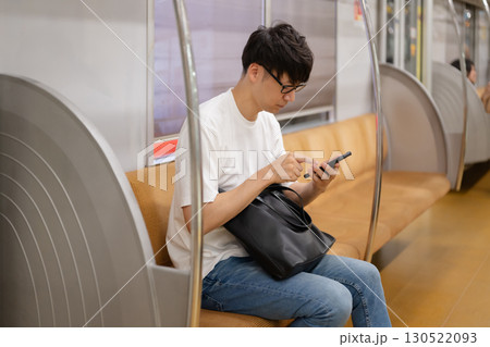 電車内でスマホを見る男性 130522093